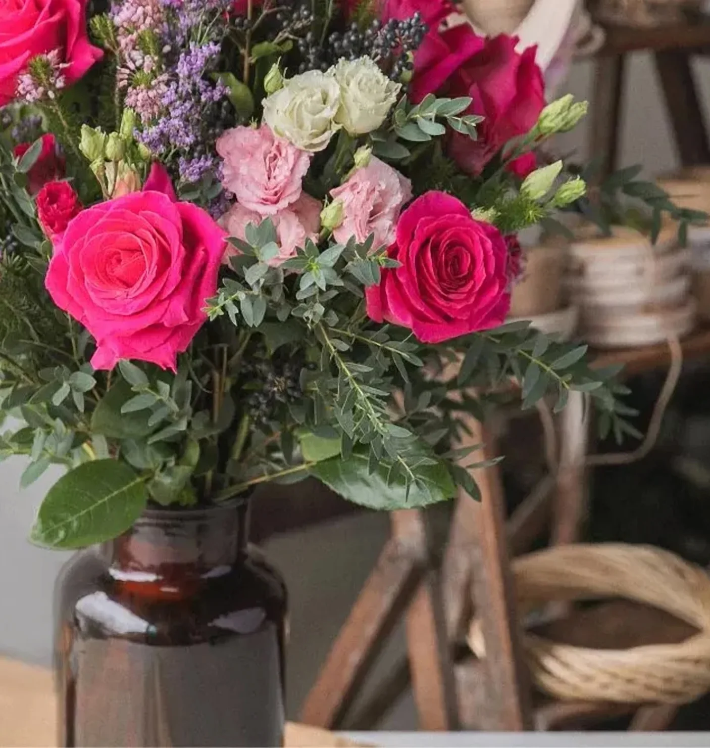 Bouquet de roses fuchsia dans un vase ambré, à l’atelier de la boutique