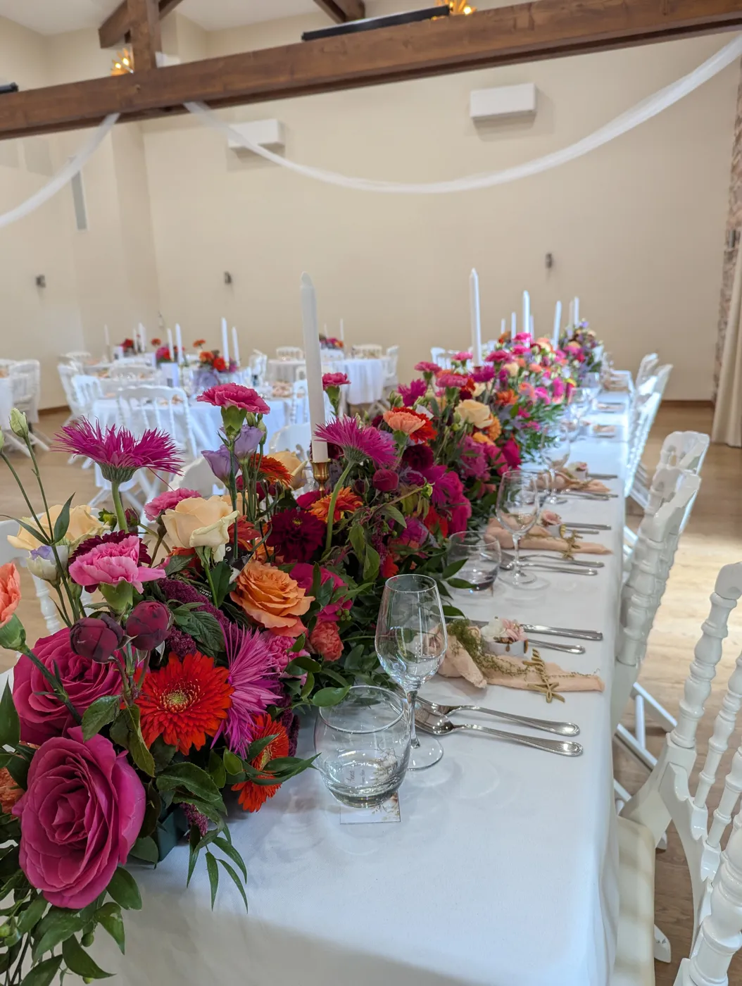 Longue table de réception fleurie de roses, dahlias et gerberas