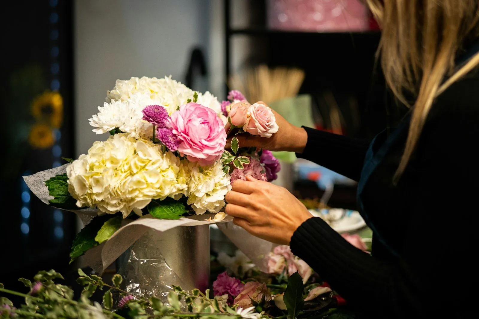 Fleuriste composant un bouquet d’hortensias et de roses