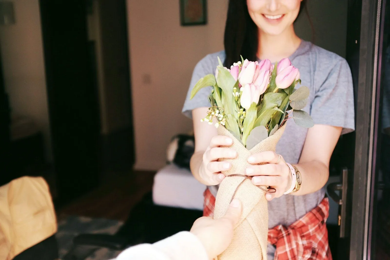 Une jeune femme reçoit un bouquet de tulipes roses emballé dans du papier kraft