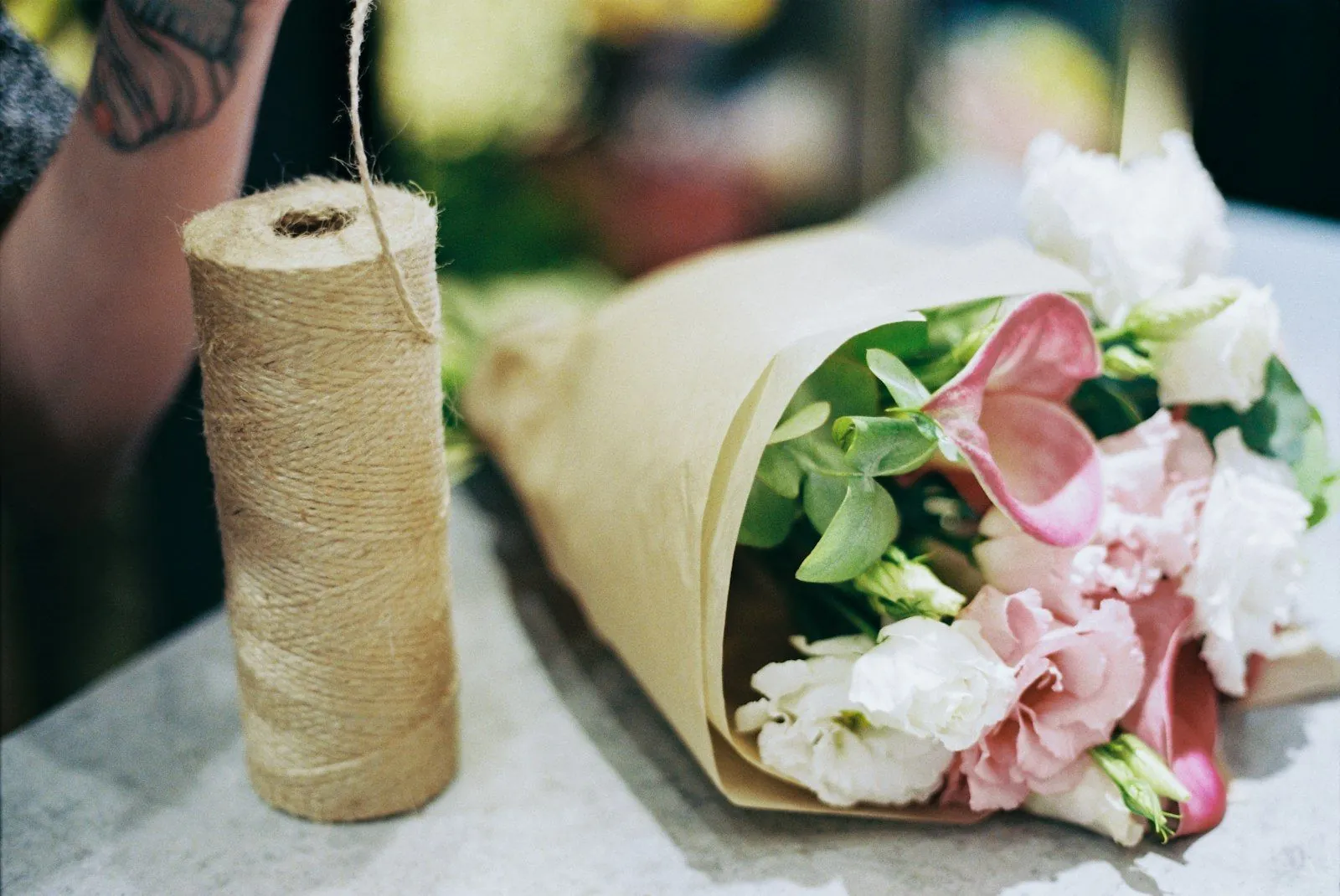 Bouquet emballé dans du papier kraft, prêt à partir en livraison, à côté d’une bobine de ficelle
