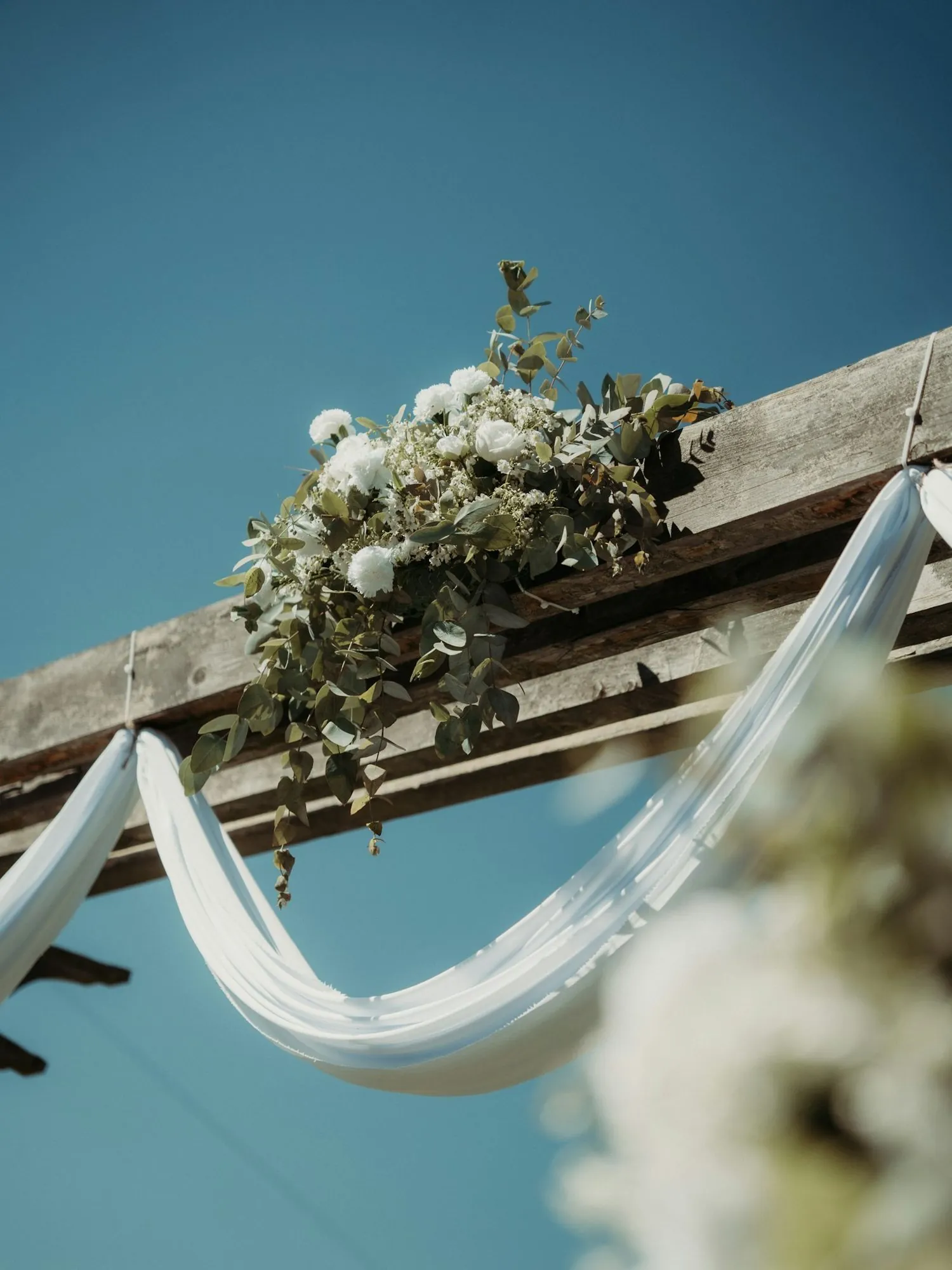Arche de cérémonie drapée de voile blanc et fleurie de blanc